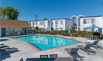 A swimming pool with chairs around it in front of a building